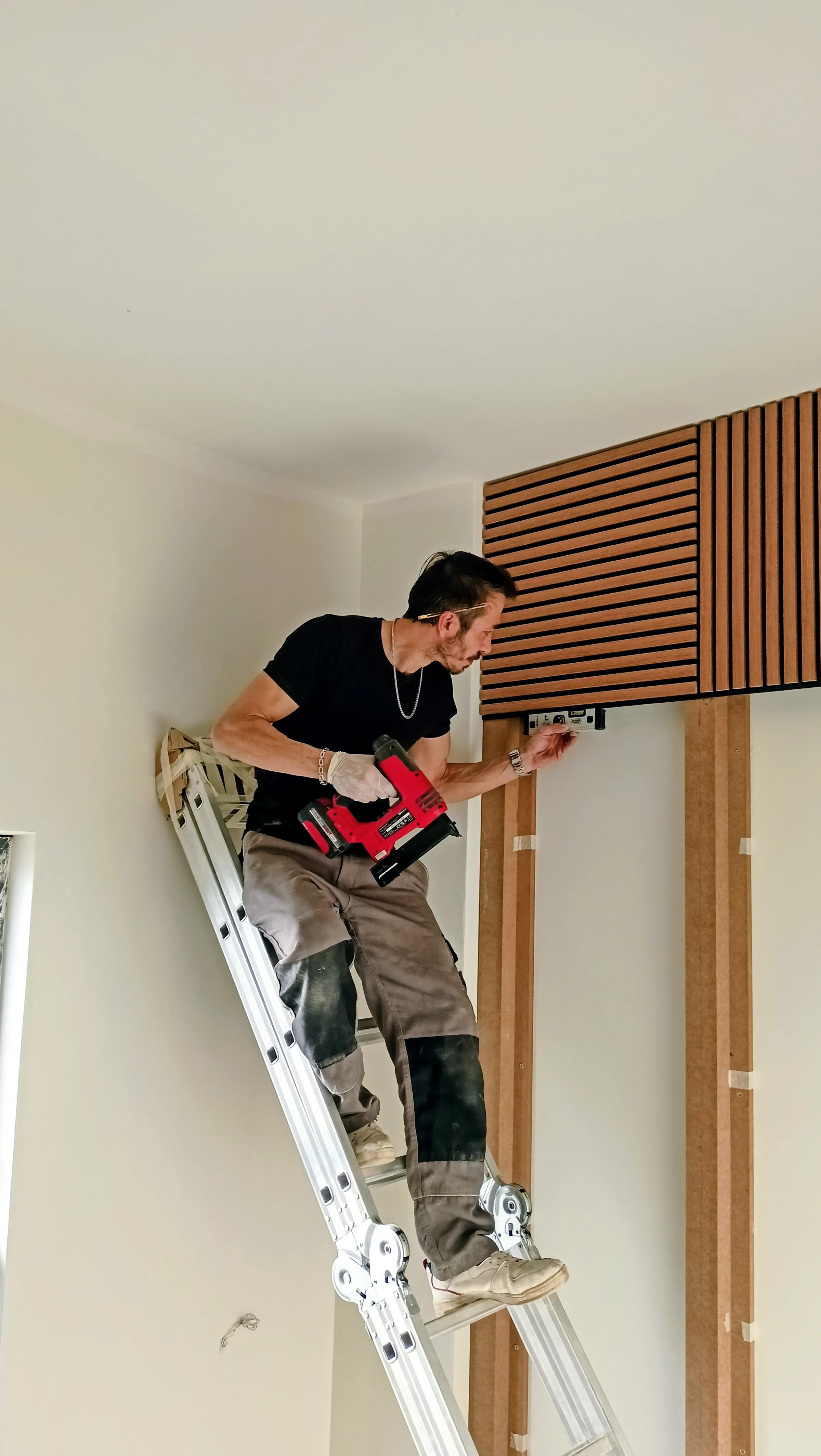 A panel being fixed to the wall from a ladder during installation.