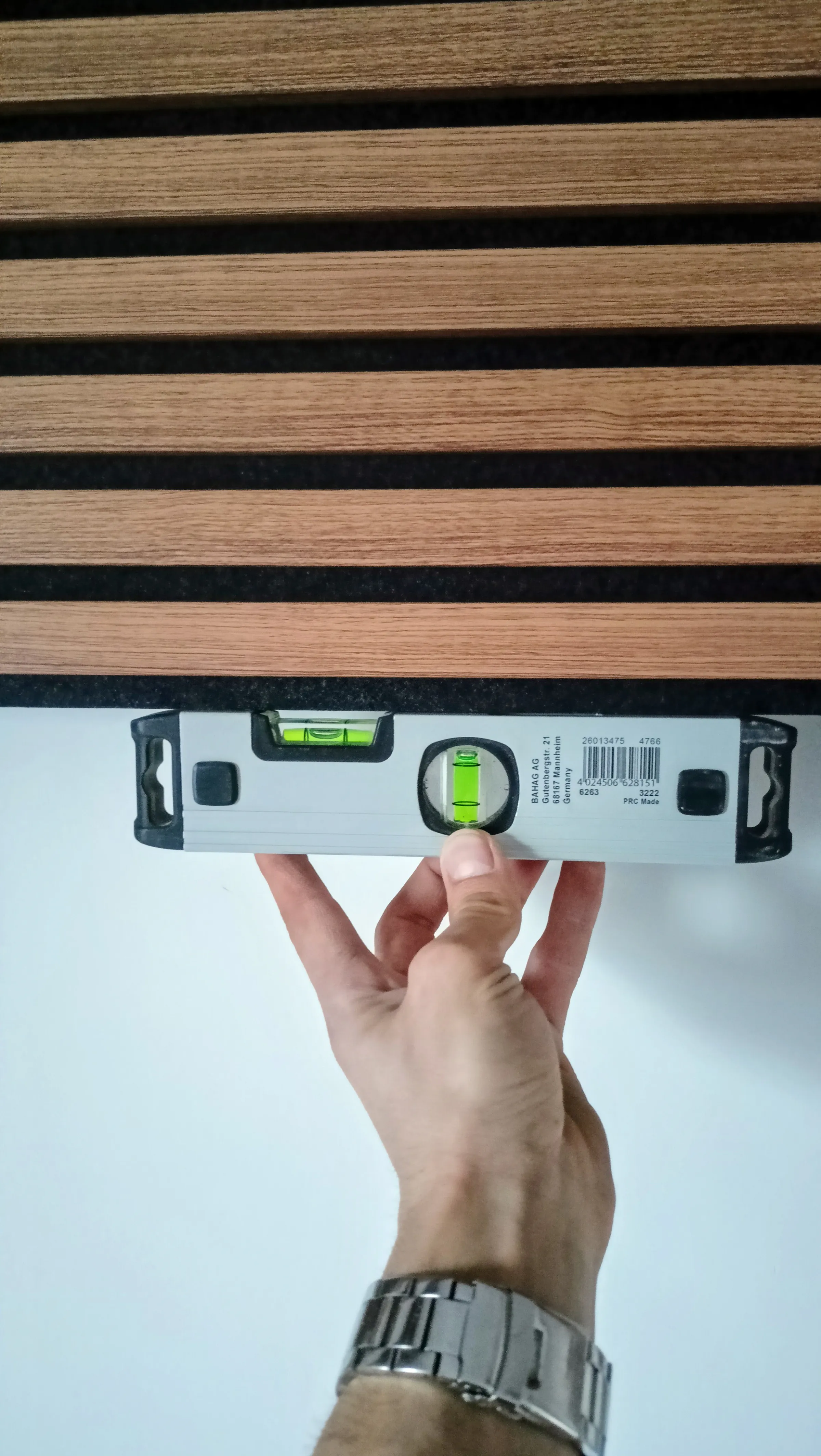 A spirit level held against the wall before the next panel goes on.