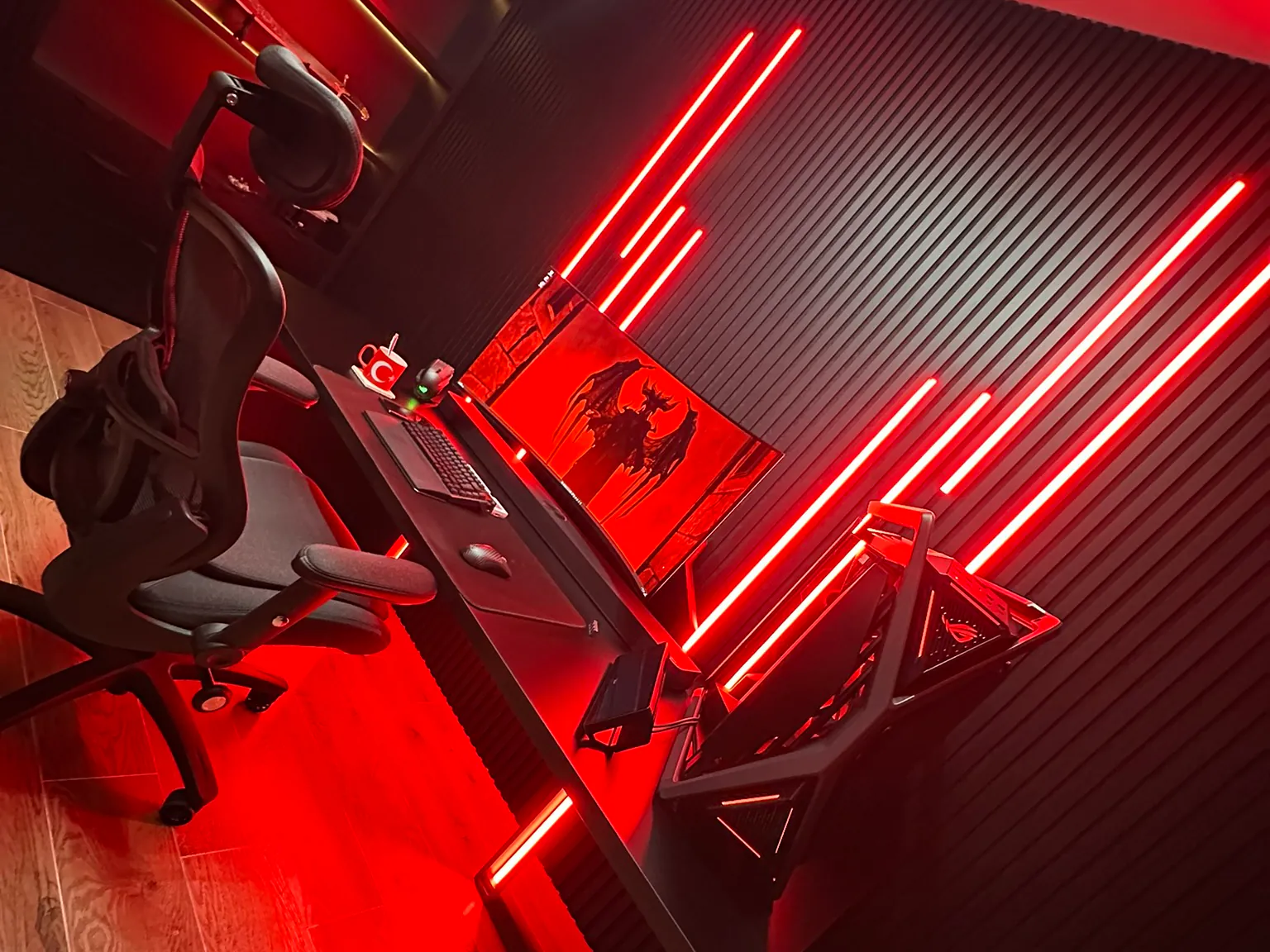 A study lined in black slatted panels, the lighting switched to red, with a desk and chair on an oak floor.