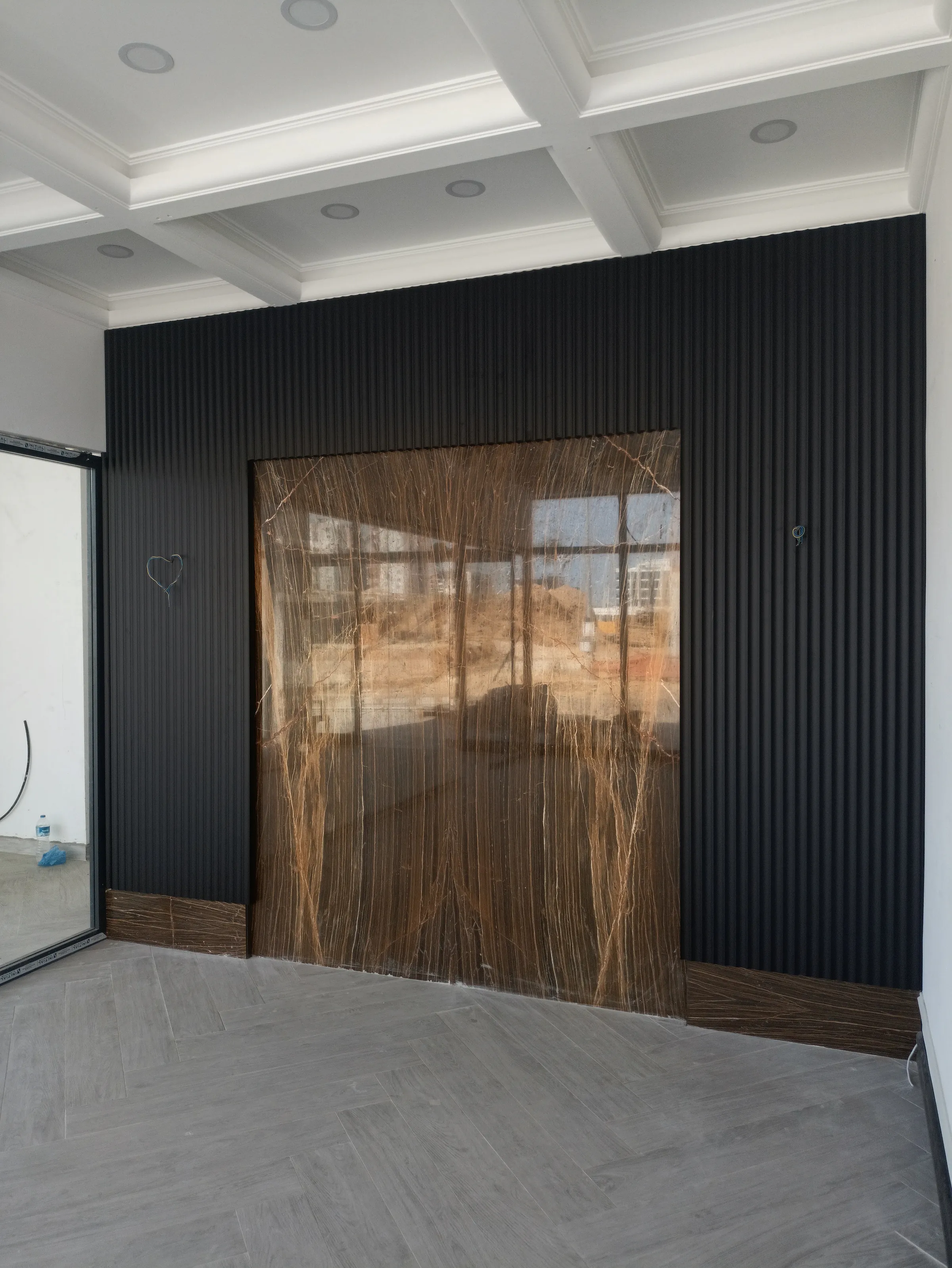 A charcoal slatted wall around a wide wood-framed glass door opening to the garden.
