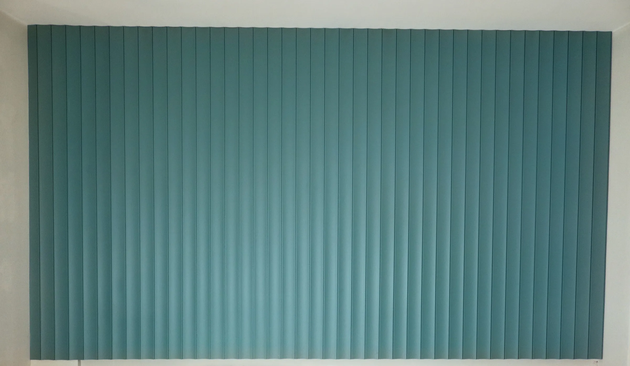A fluted wall panel painted green, its ribs narrow and evenly spaced.