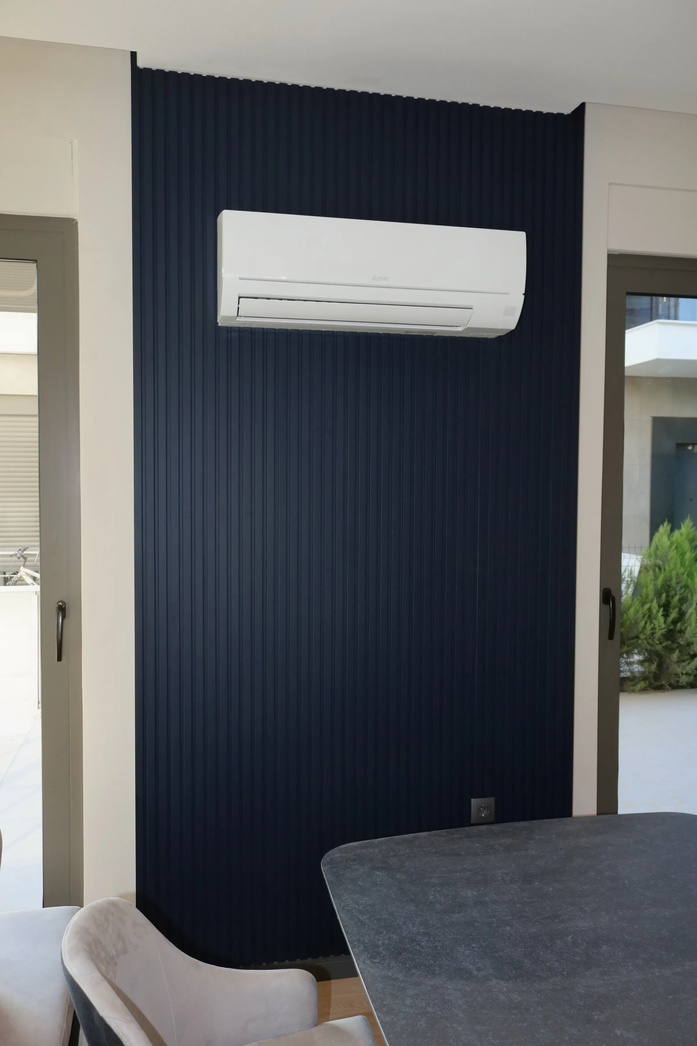 A navy fluted wall behind a dining table, with glazing onto the garden beside it.