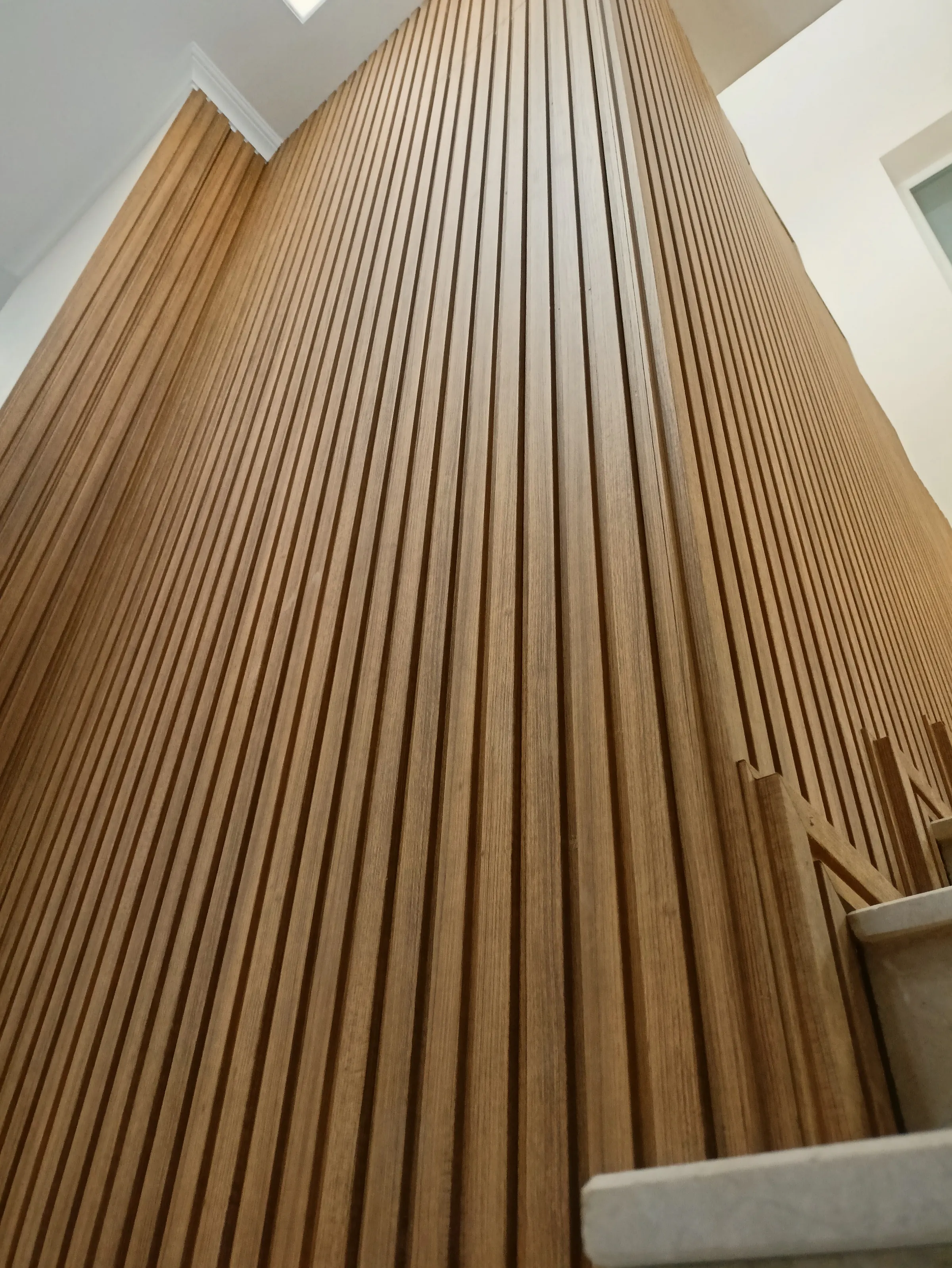 Oak slats running up a stairwell, narrowing together as they reach the ceiling.